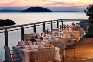 a group of tables on a balcony with a view of the water at Porto Carras Meliton in Neos Marmaras