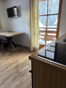 eine Küche mit einem Schreibtisch, einem Tisch und einem Fenster in der Unterkunft Apartment Steinbock in Samnaun