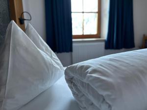 ein weißes Bett mit weißer Bettwäsche und blauen Vorhängen in der Unterkunft Apartment Steinbock in Samnaun