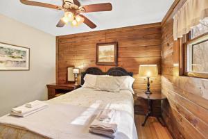 um quarto com uma cama e uma ventoinha de tecto em Picturesque Riverside Cabin with Fireplace and Porch em Blowing Rock