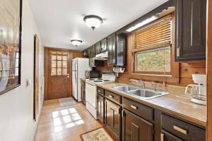 uma cozinha com armários de madeira, um lavatório e uma janela em Picturesque Riverside Cabin with Fireplace and Porch em Blowing Rock