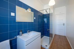 uma casa de banho em azulejos azuis com um lavatório e um chuveiro em Casa do Largo-vista sobre Lisboa em Lisboa