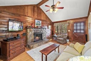 a living room with a fireplace and a ceiling fan at Quiet cabin in the High Country in Blowing Rock