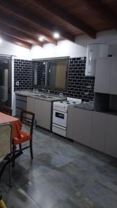 a large kitchen with white appliances and a table at La morada del arroyo in Villa Santa Cruz del Lago