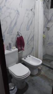a white bathroom with a toilet and a sink at La morada del arroyo in Villa Santa Cruz del Lago