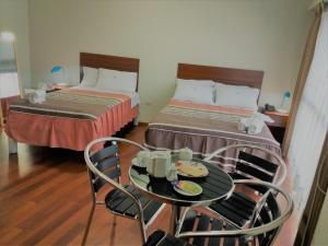 a hotel room with two beds and a table and chairs at HOTEL MURCIA AREQUIPA in Arequipa
