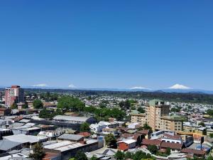een stad met gebouwen en bergen op de achtergrond bij Departamento central con estacionamiento in Temuco