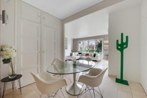 a dining room with a glass table and white chairs at Bel appartement 3 pièces 2 chambres 76M2 + balcon + Parking in Neuilly-sur-Seine