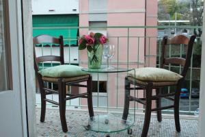 une table avec deux chaises et un vase de fleurs sur le balcon dans l'établissement Holiday Relax, à La Spezia