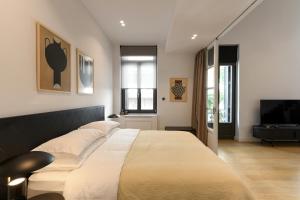 a bedroom with a large bed and a flat screen tv at Boutique Archaeological Museum Suites in Athens