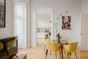 uma sala de jantar com uma mesa de vidro e cadeiras amarelas em Architectural Gem in Baixa em Lisboa