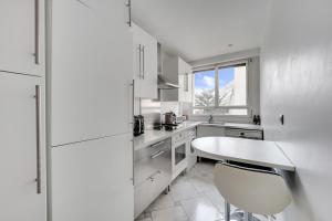 a white kitchen with a table and a window at Bel appartement 3 pièces 2 chambres 76M2 + balcon + Parking in Neuilly-sur-Seine