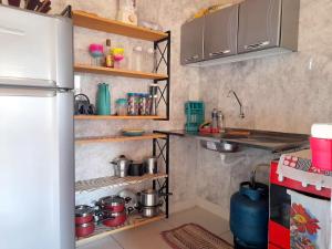 a kitchen with pots and pans on shelves next to a refrigerator at Chalé R Paz Macapá in Luis Correia