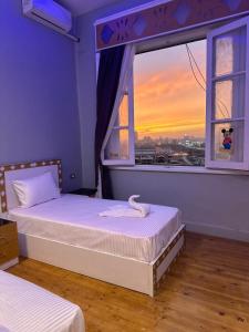 1 dormitorio con 2 camas y una ventana con puesta de sol en Midtown Nile View Suites en El Cairo