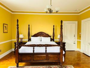 a bedroom with a wooden bed with yellow walls at The Hamilton Hoppin House in Middletown