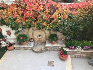 um ramo de flores numa parede de pedra com vasos de plantas em Yellow House Oropos em Néa Palátia