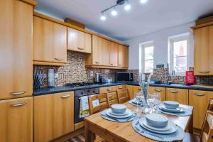 a kitchen with wooden cabinets and a table with dishes on it at Inviting 3-Bedroom House in Warrington with Parking and Free Wifi by Amazing Spaces Relocations Ltd. in Warrington