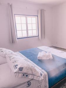 ein weißes Schlafzimmer mit einem Bett und einem Fenster in der Unterkunft Casa com churrasqueira e 3 quartos - Centro in Búzios