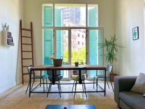 ein Wohnzimmer mit einem Tisch und Stühlen sowie einem großen Fenster in der Unterkunft Stone Wall 2BR Apartment in Beirut