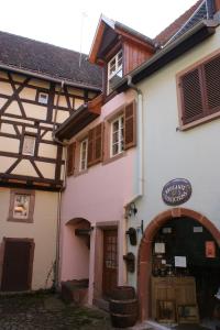 a white building with an archway next to a store at Location "Charme" in Riquewihr