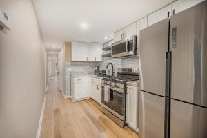 a kitchen with white cabinets and a stainless steel refrigerator at The Homey Haven - New Corporate Home Downtown in Grand Rapids