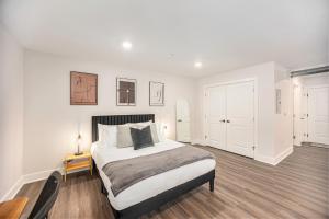 a white bedroom with a bed and a wooden floor at Cityscape Suite -brand New Corporate Apt Downtown in Grand Rapids