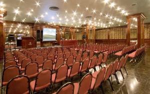 un auditorio vacío con sillas rojas y una pantalla en Hotel Presidente Buenos Aires, en Buenos Aires