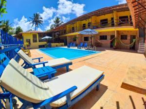 a resort with a pool and chairs and a building at Pousada Praia do Amor Pipa in Pipa