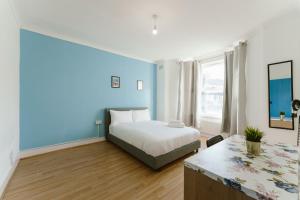 1 dormitorio con cama y pared azul en Stratford Cosy Rooms - 37, en Londres