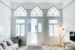 a living room with white walls and arched windows at Charming Heritage 2 BR In Mar Mikhael in Beirut