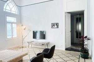 ein weißes Wohnzimmer mit einem TV und einem Tisch in der Unterkunft Charming Heritage 2 BR In Mar Mikhael in Beirut