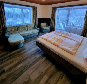 ein Schlafzimmer mit einem Bett, einem Sofa und Fenstern in der Unterkunft Guesthouse Schoba Typ A in Kirchbach