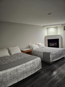 2 camas en una habitación de hotel con chimenea en Western Budget Motel #1 Leduc/Nisku en Leduc