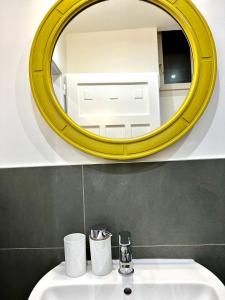 a bathroom with a yellow mirror above a sink at Baker House in Bolzano