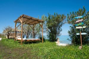 a wooden gazebo with a bench next to the ocean at YOLO Resort- Giardino in Alykes