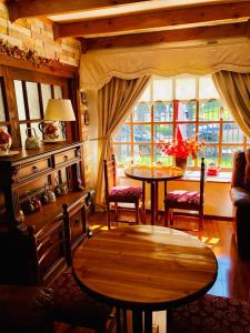 sala de estar con mesa, sillas y ventanas en Hostal Collins House, en Temuco