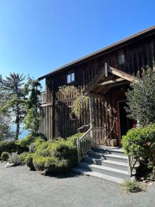 a wooden house with stairs leading to the door at French Beach House Shirley BC in Shirley