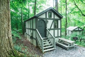 a playhouse with a staircase and a bench in the woods at Tiny Home Cottage Near the Smokies #5 Fleur in Sevierville