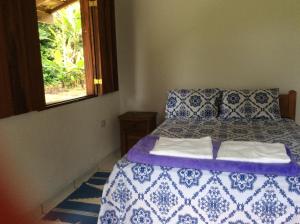 Un dormitorio con una cama azul y blanca y una ventana en Chalé da Jane en Parati