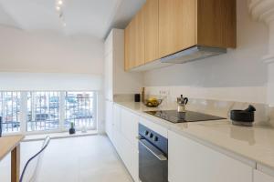 Una cocina con encimeras blancas y gabinetes de madera. en Stylish Apartment near Plaça España, en Barcelona
