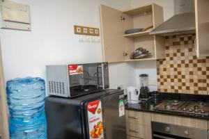 uma cozinha com um frigorífico e um micro-ondas em cima em Madaraka 2 Bed apartment with Rooftop pool. em Nairobi
