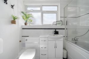 a white bathroom with a sink and a bath tub at Stylish 3 Bed with Outdoor space in Vibrant East London in London