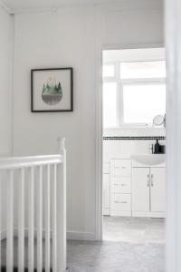 a white kitchen with a staircase and a sink at Stylish 3 Bed with Outdoor space in Vibrant East London in London