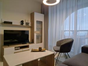 ein Wohnzimmer mit einem TV und einem Stuhl in der Unterkunft LUXURY APARTMENT in Mediterranea VARNA Complex, sea view and Infinity pool in Warna