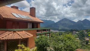 a house with a roof with a view of mountains at Villa Alto das Montanhas/Friburgo in Nova Friburgo