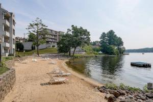 a beach with lounge chairs and a boat in the water at WFC IV Adults or Families Lakefront View in Wisconsin Dells
