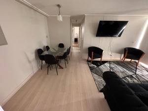 sala de estar con mesa, sillas y TV en Depto Completo a 15 minutos del aereopuerto y frente al Mall, en Santiago