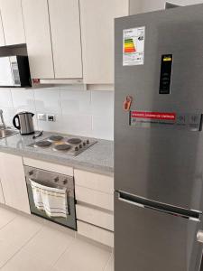 a stainless steel refrigerator in a kitchen with white cabinets at Depto Completo a 15 minutos del aereopuerto y frente al Mall in Santiago