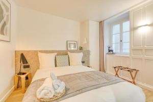 ein weißes Schlafzimmer mit einem Bett und einem Handtuch darauf in der Unterkunft Git le cœur in Paris