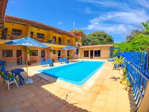 a pool with chairs and umbrellas next to a house at Pousada Praia do Amor in Pipa